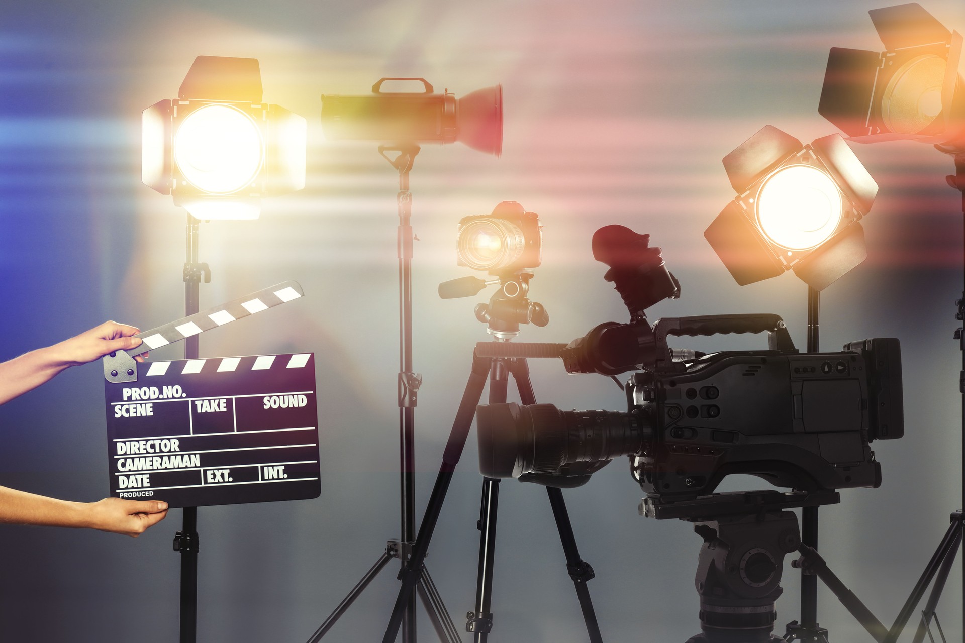Femme avec clapperboard près d’une caméra vidéo professionnelle moderne en studio, gros plan